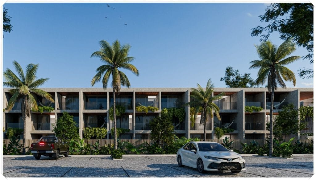 Prédio de estilo moderno com palmeiras, carros estacionados e vegetação ao redor, sob um céu azul claro.
