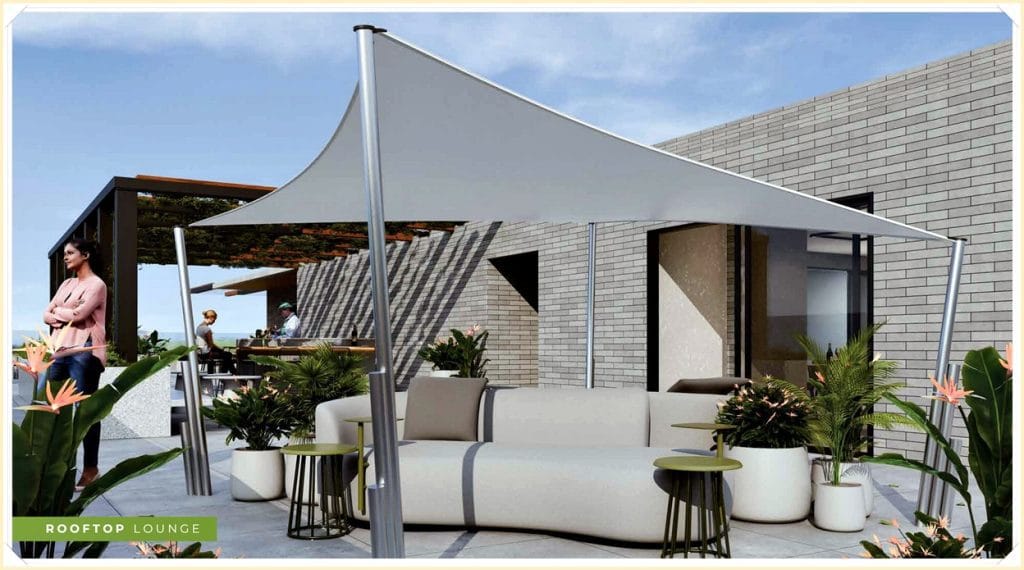 Área externa com lounge sofisticado, sofás claros, mesas pequenas e plantas, sob uma estrutura de sombra. Ambiente moderno e convidativo.