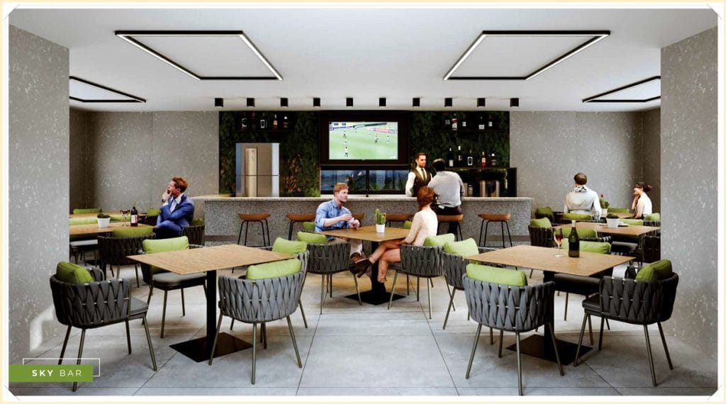 Ambiente moderno com mesas e cadeiras, pessoas conversando e assistindo TV, bar ao fundo com bebidas e decoração elegante.