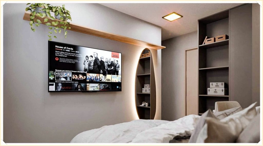 Quarto moderno com uma cama de lençóis claros, prateleiras organizadas e uma TV na parede exibindo "House of Cards".