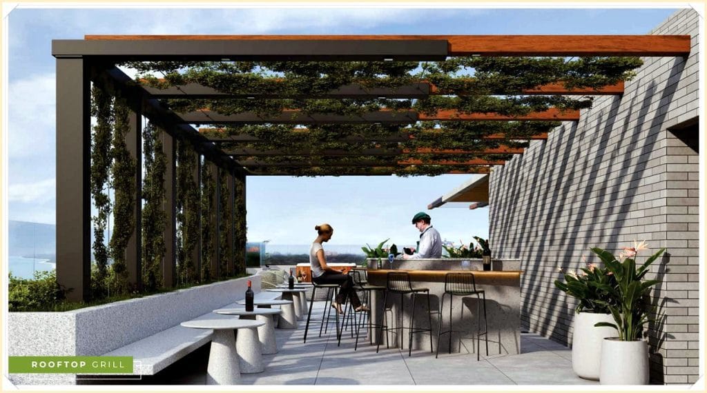 Área de lazer com churrasqueira no rooftop, mesas e cadeiras modernas, vista panorâmica e vegetação ao fundo.