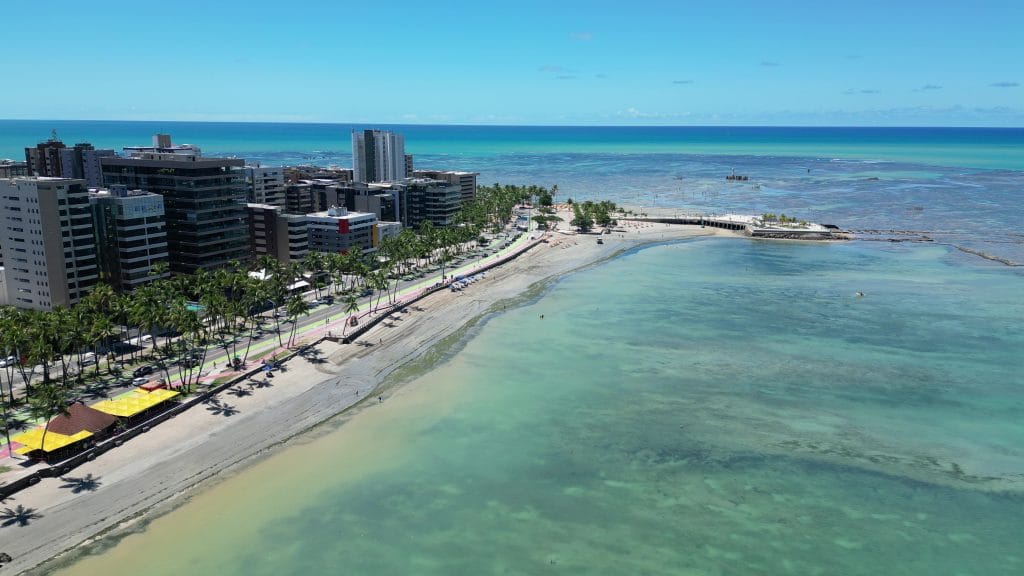Praia de Ponta Verde em Maceió, Alagoas, com calçadão e prédios à beira-mar.